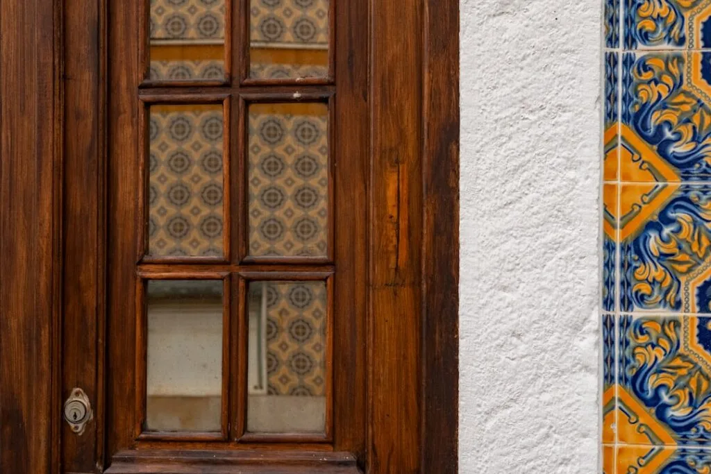 Porte en bois à petits carreaux encadrée d'azulejos colorés à Lisbonne