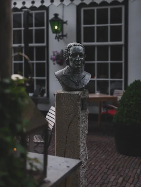 Buste en bronze posé sur un socle dans une cour pavée calme