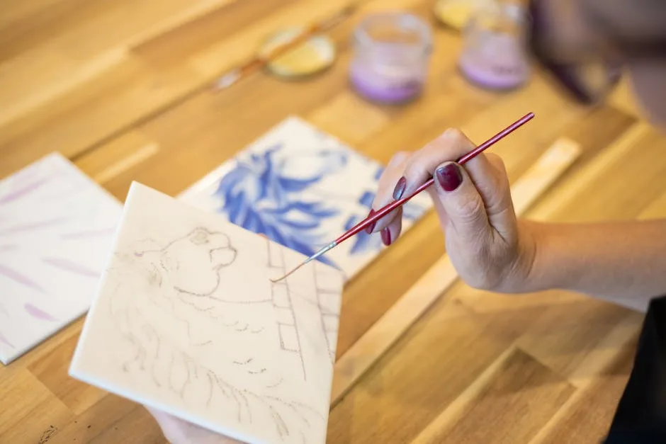 Main peignant un carreau d'azulejo à la main dans un atelier