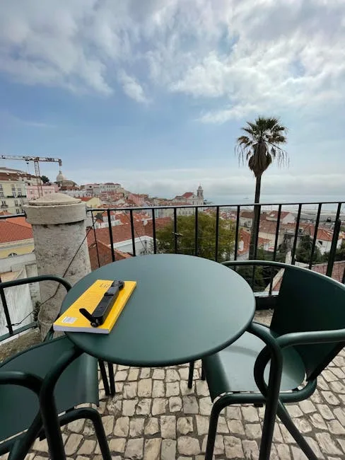 Table de terrasse verte avec carnet jaune, vue sur les toits de Lisbonne