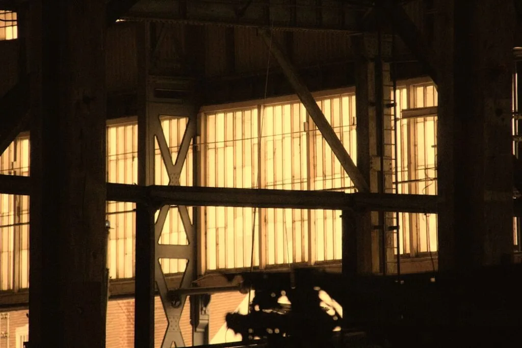 Structure métallique avec grandes fenêtres éclairées, ambiance industrielle et sombre
