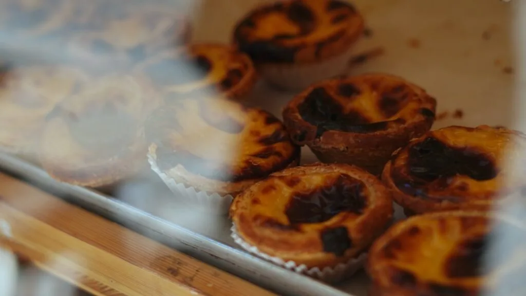 Pastéis de nata dans une vitrine avec reflets de rue à Lisbonne