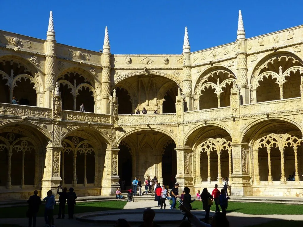 Cour du monastère des Hiéronymites à Lisbonne, façades sculptées et visiteurs.