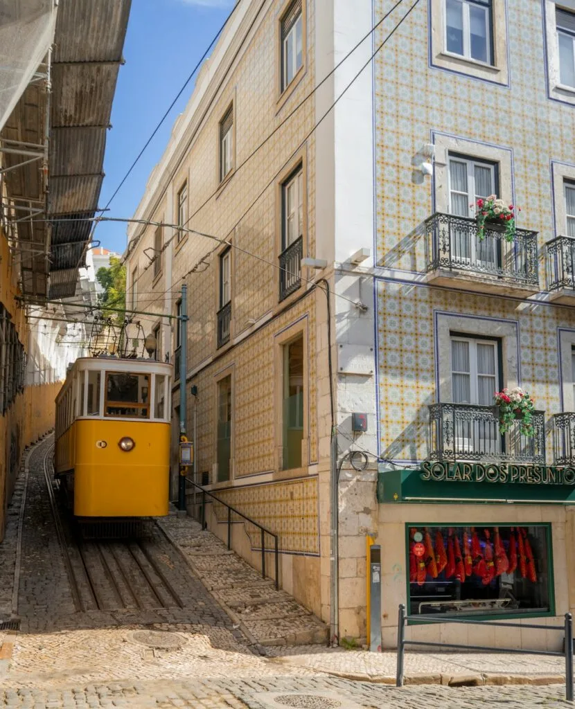 Funiculaire jaune de l'Elevador da Bica remontant une rue carrelée à Lisbonne