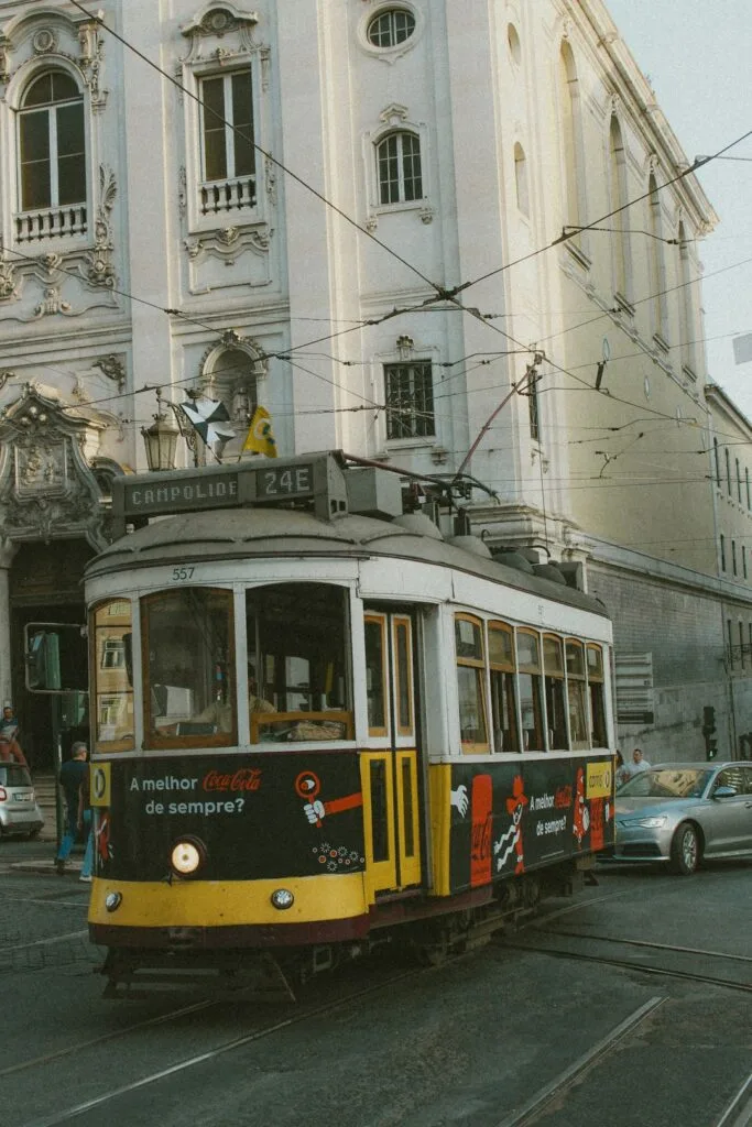 Tram jaune historique 24E circulant devant une façade ornée à Lisbonne