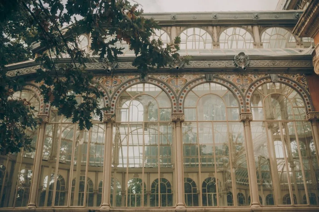 Grande serre vitrée ornée entourée d'arbres dans un jardin de Lisbonne