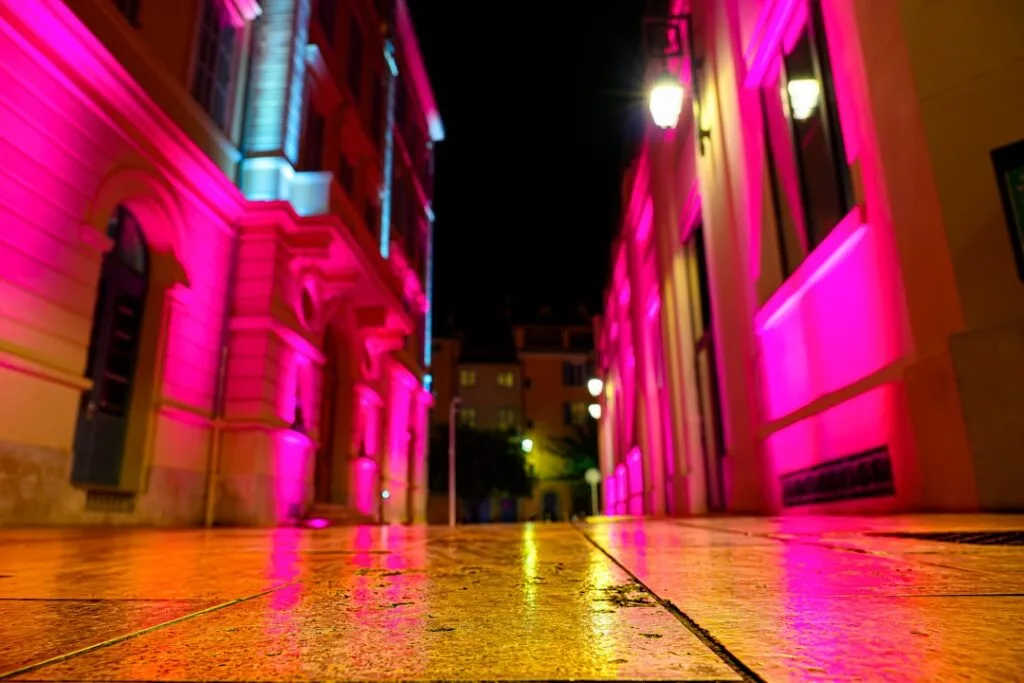 Rue nocturne de Lisbonne éclairée en rose, sol réfléchissant