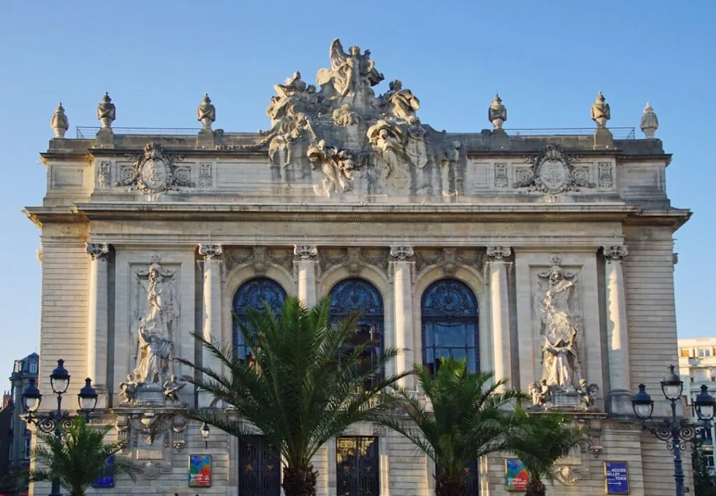 Façade monumentale ornée de sculptures et palmiers à Lisbonne