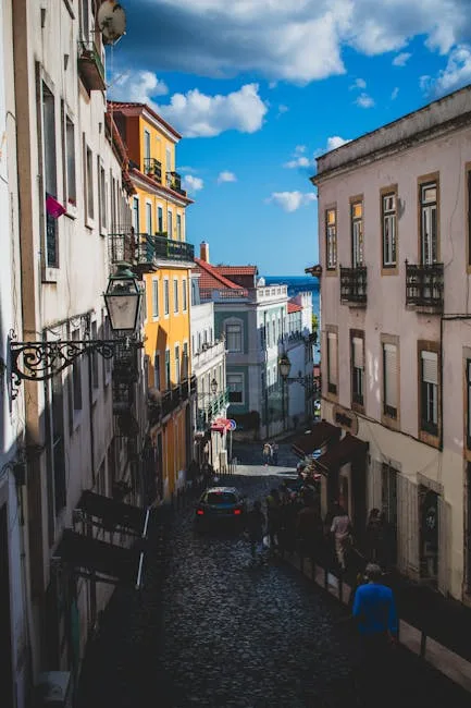 Rue en pente pavée bordée d'immeubles colorés vers le fleuve à Lisbonne