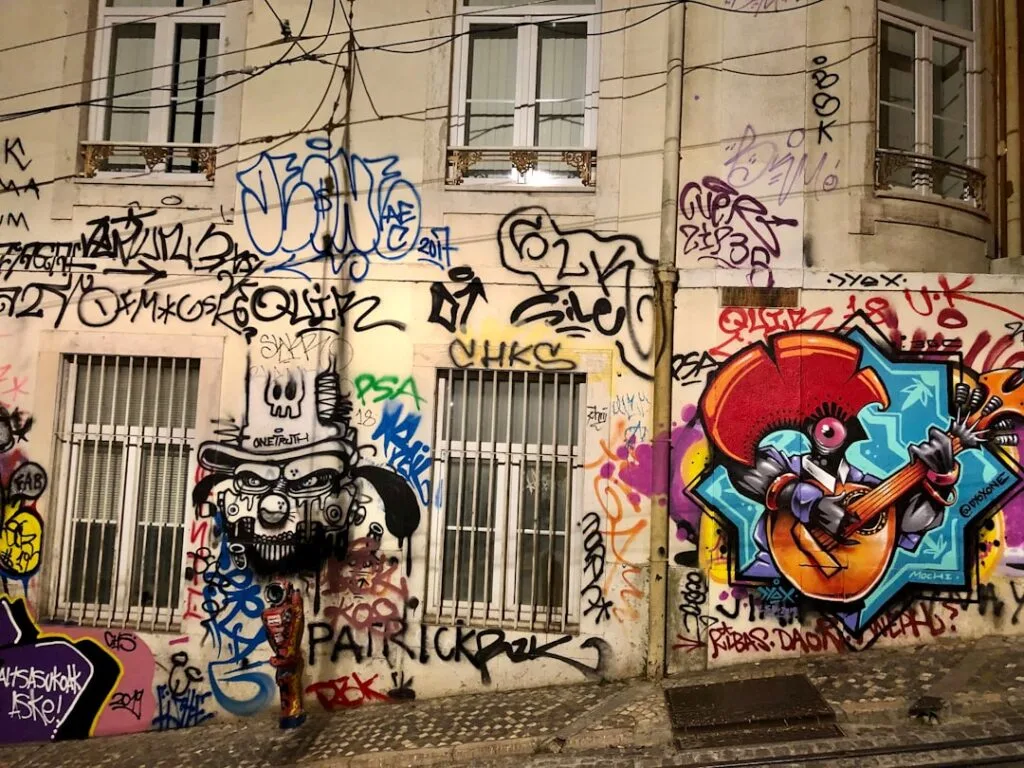 Façade couverte de graffitis colorés et fresque musicale dans une rue de Lisbonne
