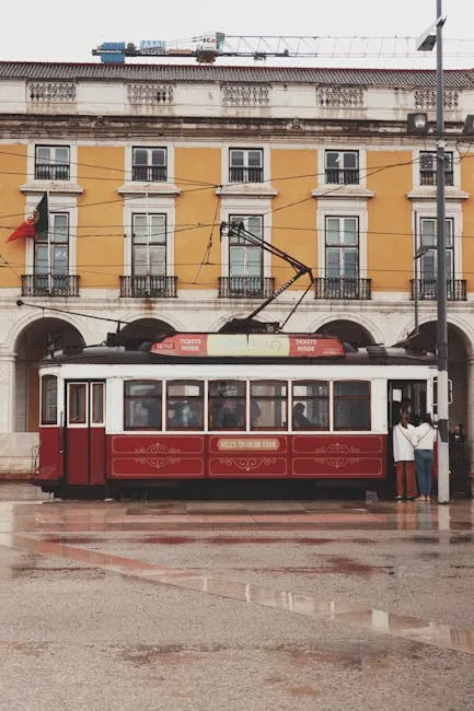 Tramway rouge stationné devant façades jaunes et arcades de Lisbonne