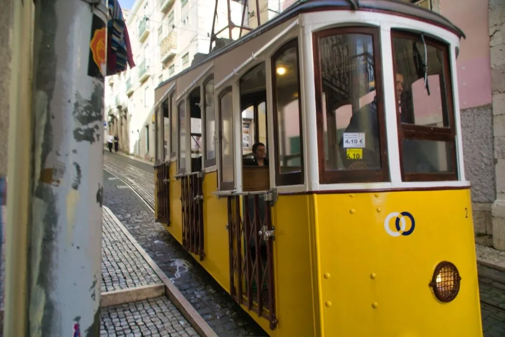 Tramway jaune serré dans une ruelle pavée de Lisbonne, intérieur visible