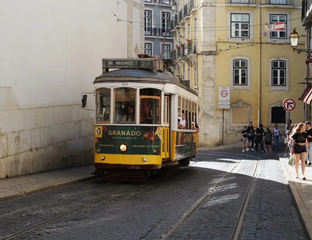 Tram jaune de la ligne 28 montant une rue pavée de Lisbonne