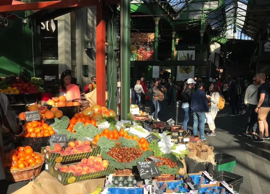 Grande halle marchande animée avec étals de fruits et clients