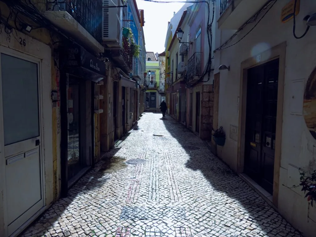 Ruelle étroite pavée à Lisbonne, silhouette marchant vers l'éloignement