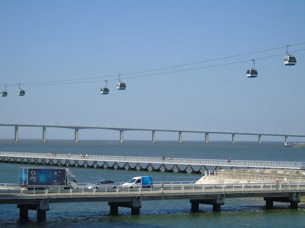 Cabines aériennes du téléphérique du Tage à Lisbonne, pont et océan en arrière-plan.