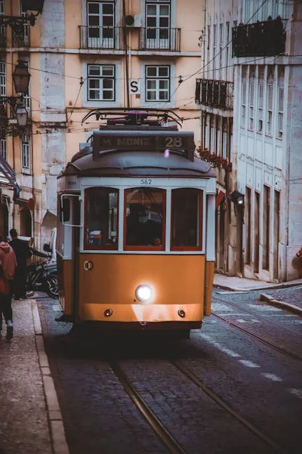 Tramway jaune n°28 descendant une rue étroite et pavée de Lisbonne.