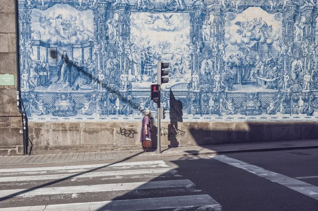 Femme attendant au feu devant un grand panneau d'azulejos à Lisbonne
