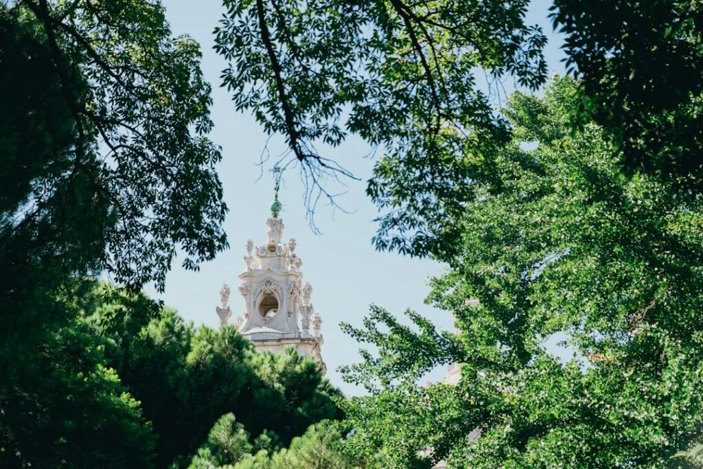Clocher baroque encadré par feuillage verdoyant à Lisbonne