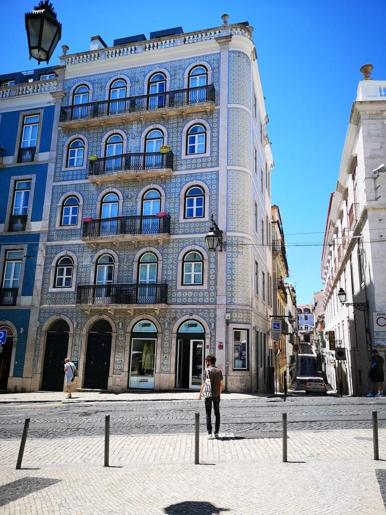 Façade carrelée d'immeuble lisboète aux balcons noirs sous ciel bleu