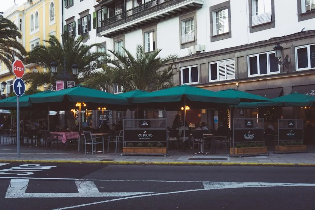 Grande terrasse bordant une avenue à Lisbonne, parasols verts et palmiers