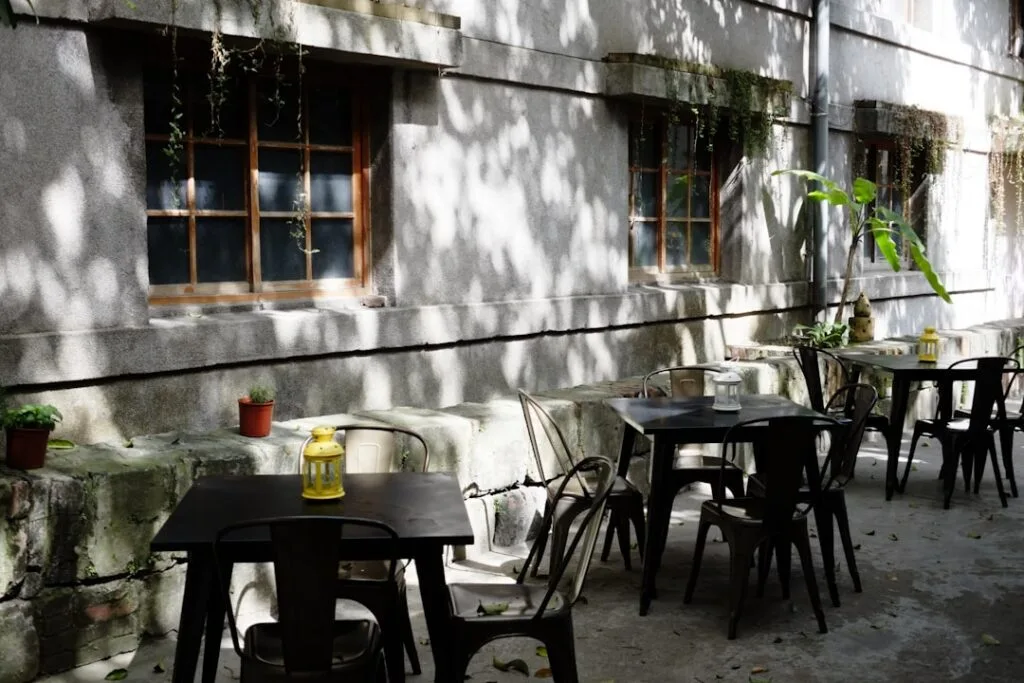 Terrasse ombragée avec tables métalliques et lanterne jaune à Lisbonne